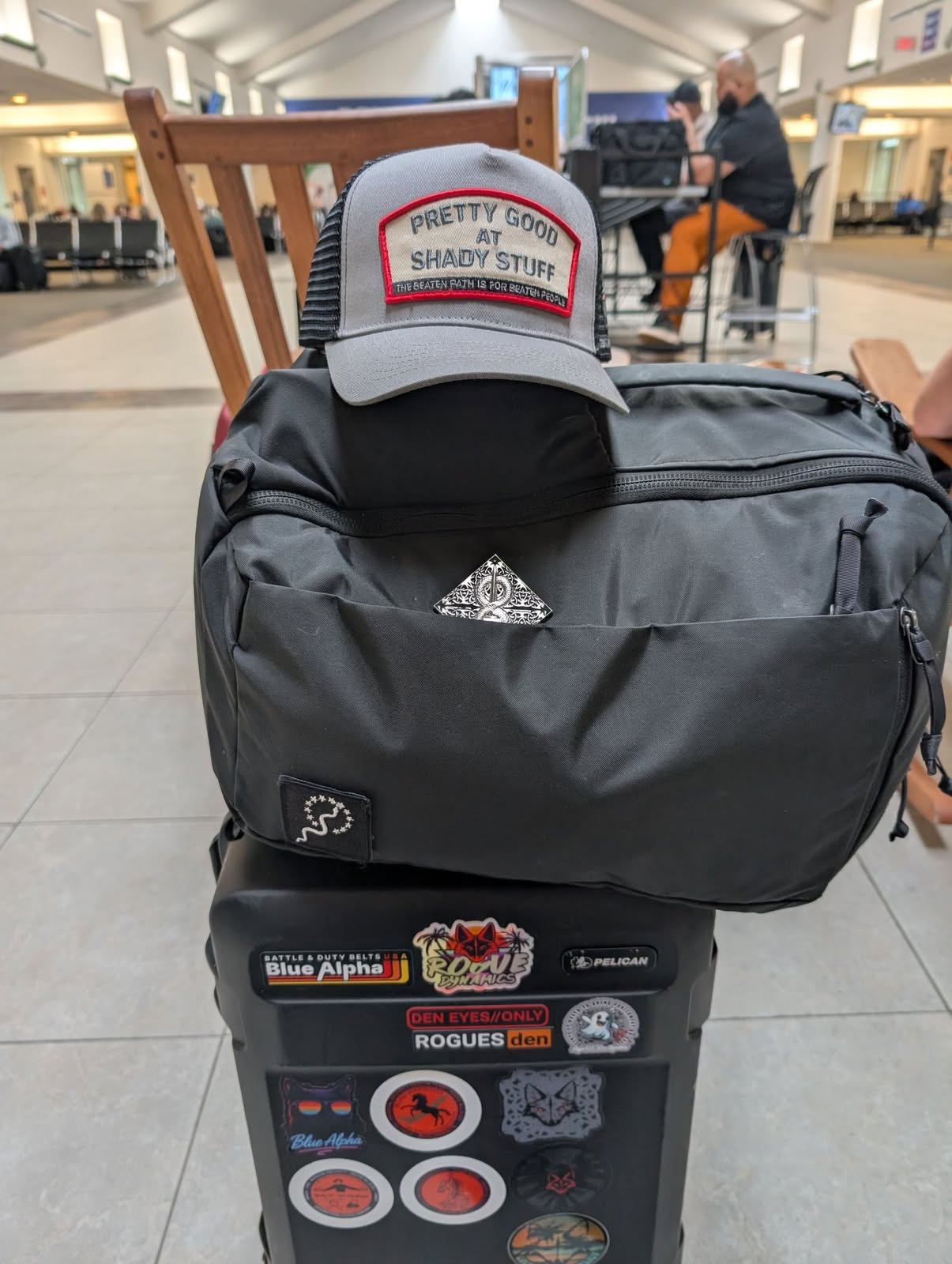 Pretty Good at Shady Stuff hat riding on a travel duffel at the airport