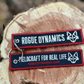 Rogue Dynamics Fieldcraft jet tag keychain showing both embroidered sides on a wood round