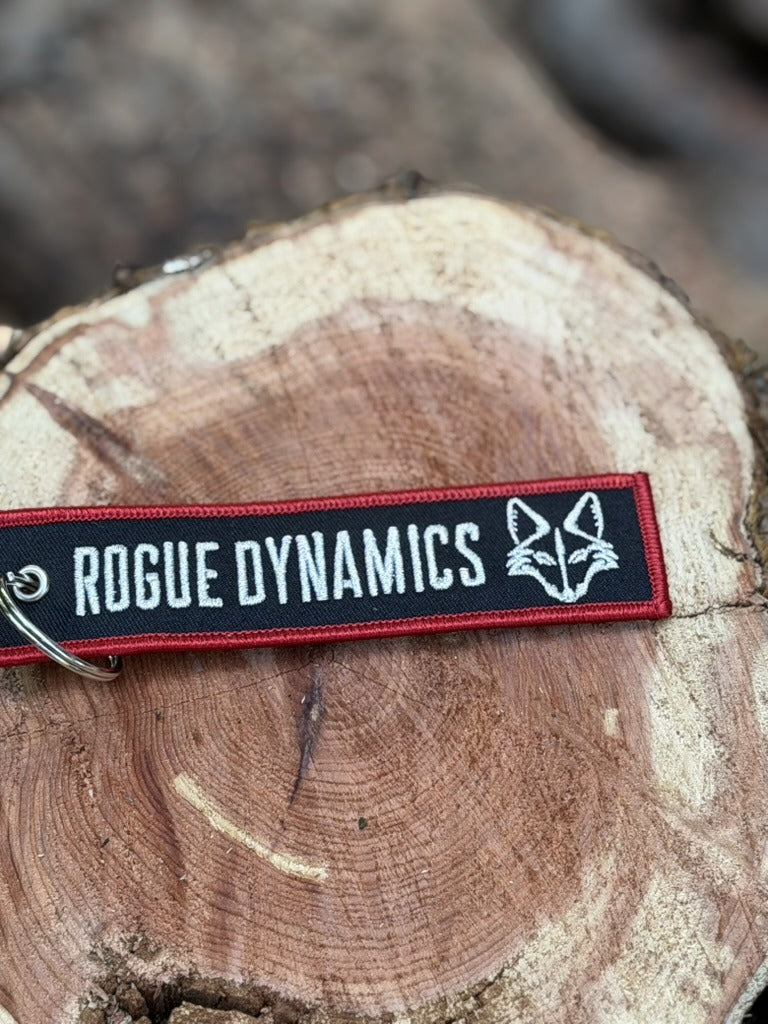 Rogue Dynamics jet tag keychain front side with white lettering, red border, and fox logo
